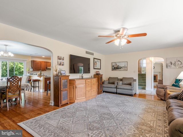 living room with ceiling fan with notable chandelier and light hardwood / wood-style flooring