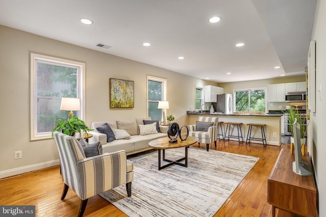 living room with light hardwood / wood-style floors and sink