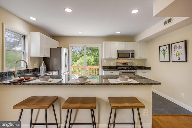 kitchen with stainless steel appliances, sink, dark hardwood / wood-style flooring, and a kitchen breakfast bar