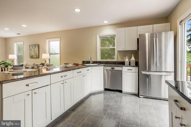 kitchen with appliances with stainless steel finishes, a healthy amount of sunlight, sink, and white cabinets