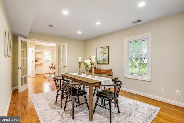 dining space with plenty of natural light, light hardwood / wood-style flooring, and french doors