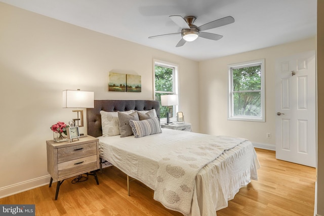 bedroom with multiple windows, ceiling fan, and light hardwood / wood-style floors