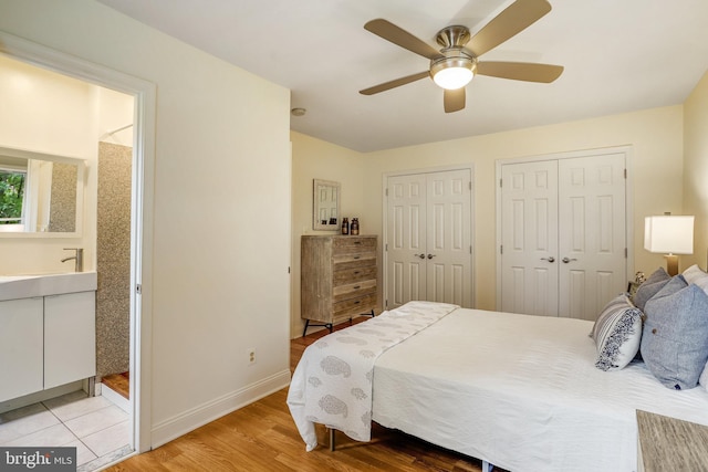 bedroom featuring two closets, ceiling fan, and light hardwood / wood-style flooring