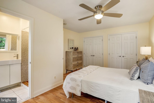 bedroom with light hardwood / wood-style flooring, two closets, and ceiling fan