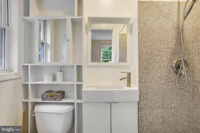 bathroom featuring vanity, toilet, and a tile shower