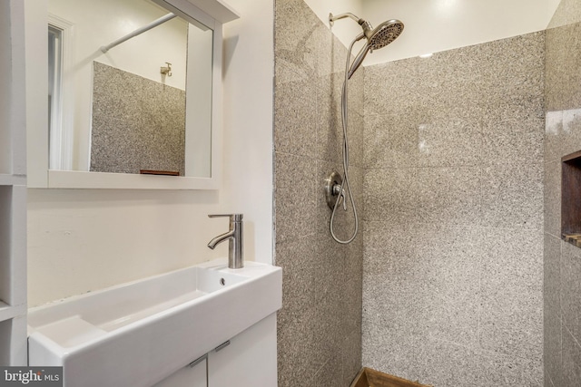 bathroom with tiled shower and vanity