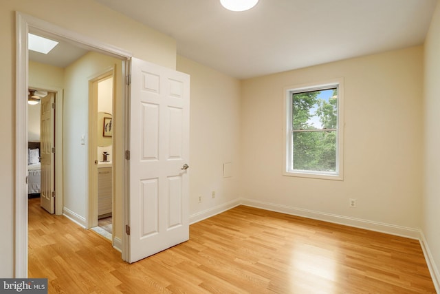 unfurnished room featuring a skylight and light hardwood / wood-style floors