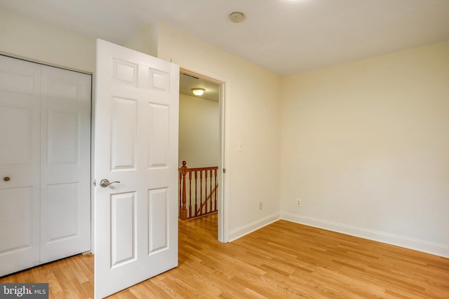 unfurnished bedroom with light wood-type flooring and a closet