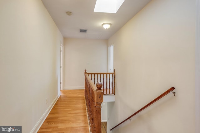 hall with light wood-type flooring and a skylight