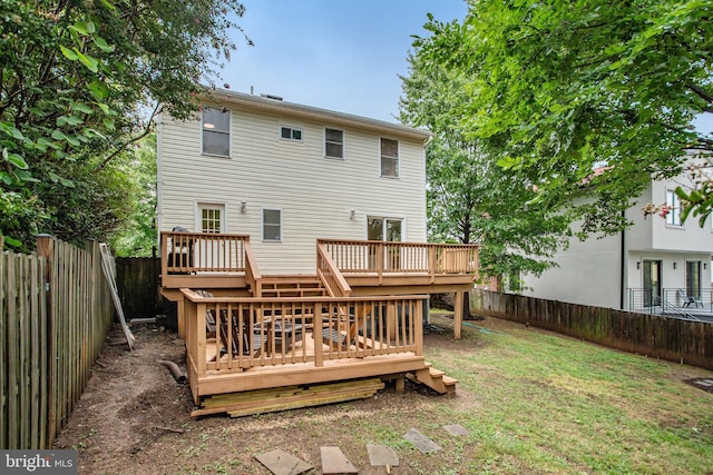 rear view of property featuring a wooden deck and a lawn