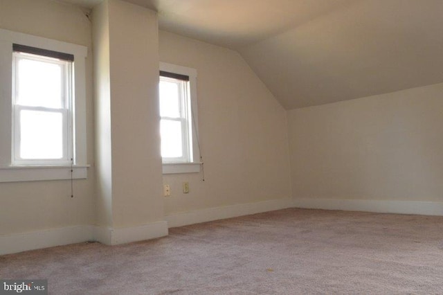 additional living space featuring lofted ceiling and light carpet