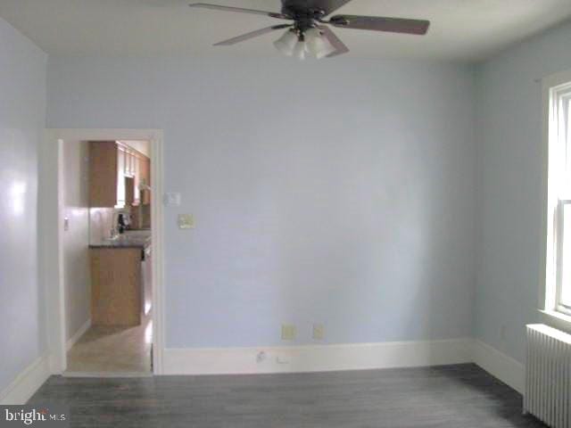 spare room with hardwood / wood-style floors, ceiling fan, and radiator