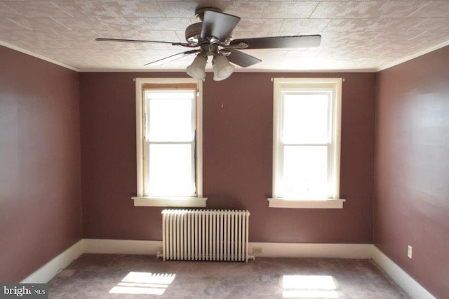 carpeted spare room with ceiling fan, plenty of natural light, and radiator heating unit