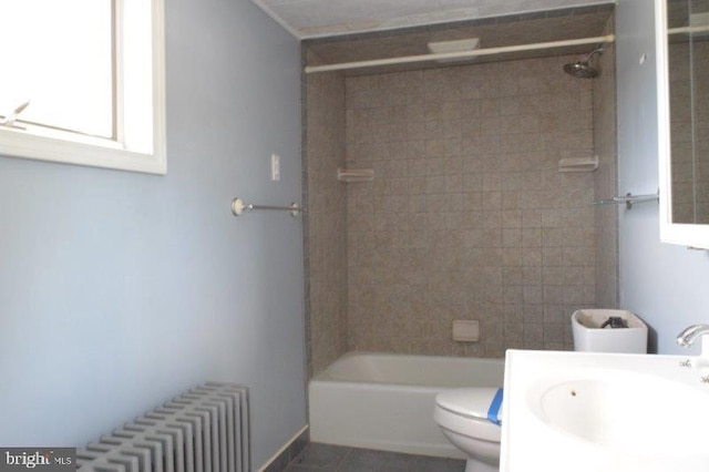 full bathroom with toilet, tile patterned flooring, tiled shower / bath, vanity, and radiator heating unit