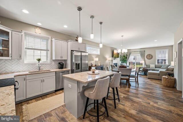 kitchen with a kitchen breakfast bar, hanging light fixtures, stainless steel appliances, a center island, and dark hardwood / wood-style floors