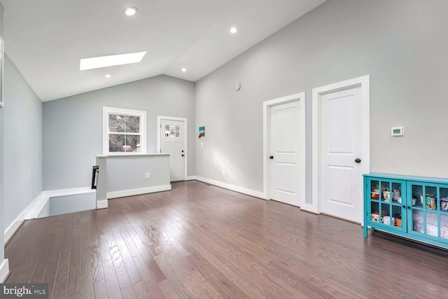 unfurnished living room with dark wood-type flooring, high vaulted ceiling, and a skylight