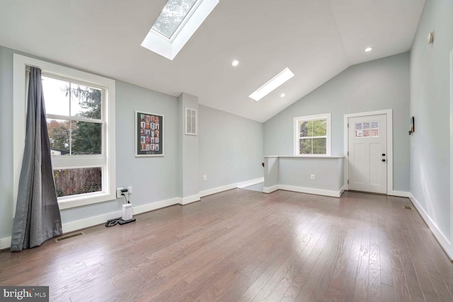 additional living space with a healthy amount of sunlight, wood-type flooring, and vaulted ceiling