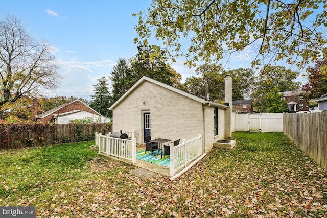 back of property featuring a wooden deck and a lawn