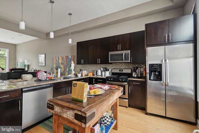 kitchen with light hardwood / wood-style flooring, light stone countertops, stainless steel appliances, sink, and decorative backsplash