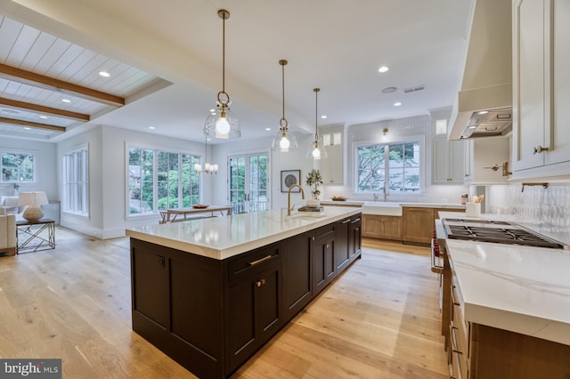 kitchen featuring sink, a wealth of natural light, a large island with sink, and beam ceiling