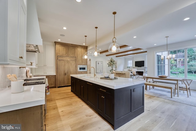 kitchen featuring hanging light fixtures, light stone countertops, light wood-type flooring, and a spacious island