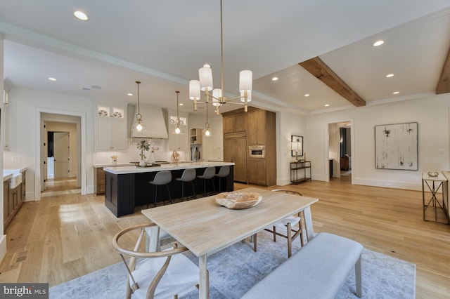 dining room with beamed ceiling, a notable chandelier, and light hardwood / wood-style floors