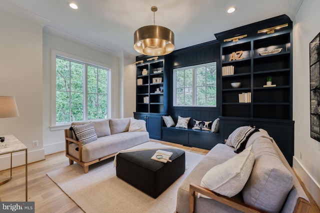 living room with a wealth of natural light, light hardwood / wood-style floors, and ornamental molding