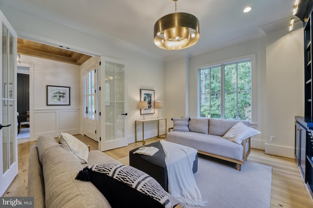 living room featuring crown molding, french doors, and light hardwood / wood-style flooring