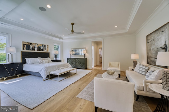 bedroom with a raised ceiling, ceiling fan, multiple windows, and light hardwood / wood-style floors