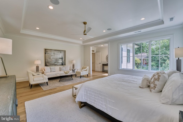 bedroom featuring crown molding, ceiling fan, light wood-type flooring, and a tray ceiling