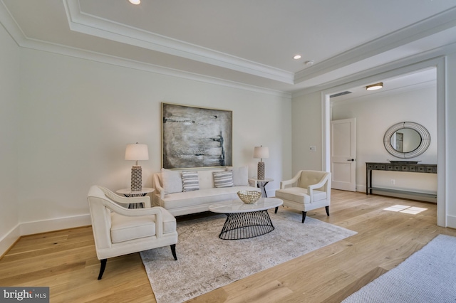 living room with ornamental molding, light hardwood / wood-style flooring, and a raised ceiling