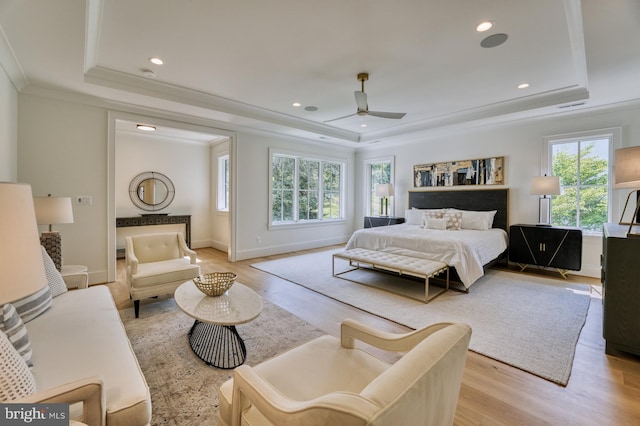 bedroom featuring a raised ceiling, ceiling fan, and multiple windows