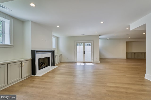 unfurnished living room featuring french doors and light hardwood / wood-style flooring