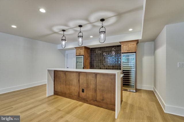 kitchen featuring hanging light fixtures, wine cooler, decorative backsplash, and light hardwood / wood-style floors