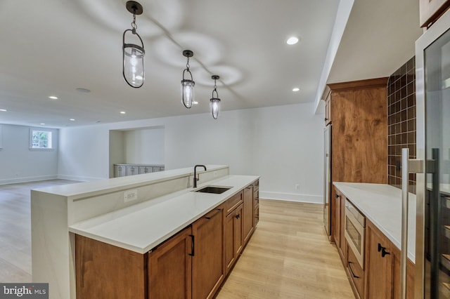 kitchen featuring decorative light fixtures, light hardwood / wood-style floors, sink, a kitchen island, and stainless steel microwave