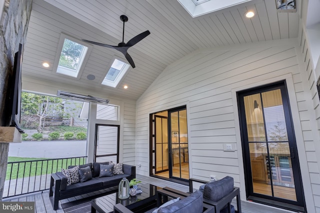 sunroom featuring wood ceiling, vaulted ceiling with skylight, and ceiling fan