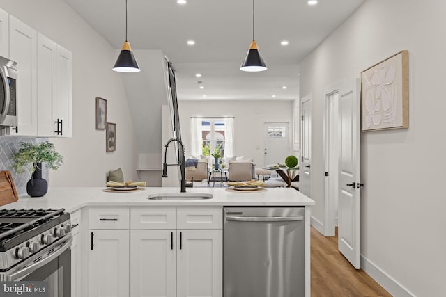 kitchen with white cabinetry, kitchen peninsula, stainless steel appliances, and sink