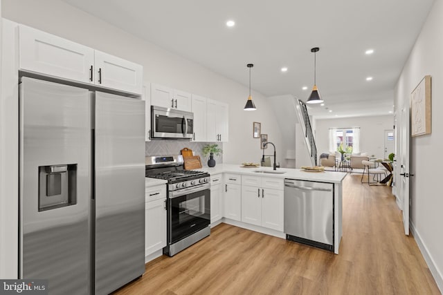 kitchen featuring appliances with stainless steel finishes, light hardwood / wood-style flooring, kitchen peninsula, and pendant lighting