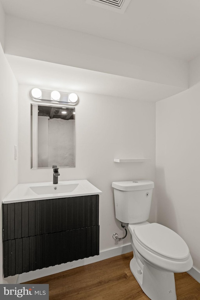 bathroom with vanity, toilet, and hardwood / wood-style floors