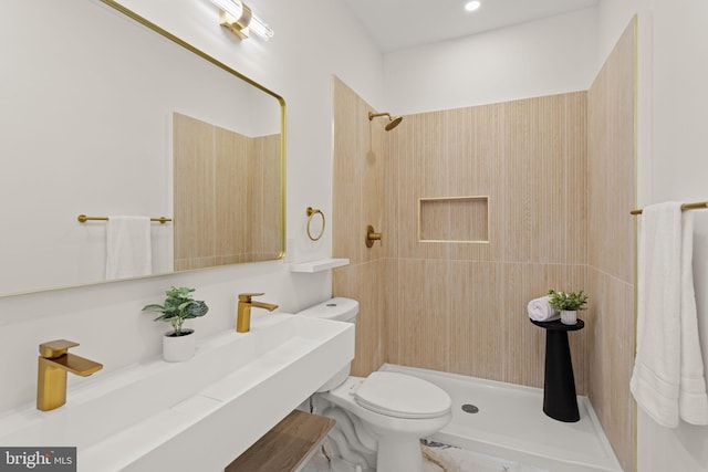 bathroom featuring tiled shower, toilet, and sink