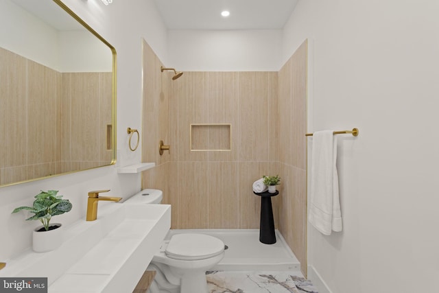 bathroom featuring vanity, toilet, and a tile shower