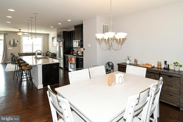 dining space featuring ceiling fan with notable chandelier, dark hardwood / wood-style floors, and sink