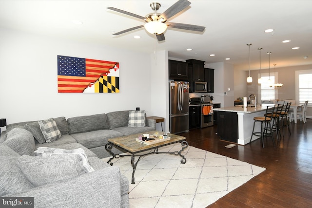 living room with dark hardwood / wood-style floors, ceiling fan, and sink