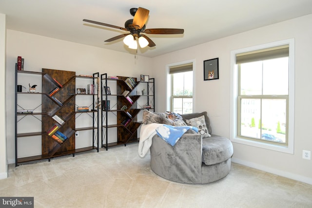 living area with ceiling fan and light colored carpet