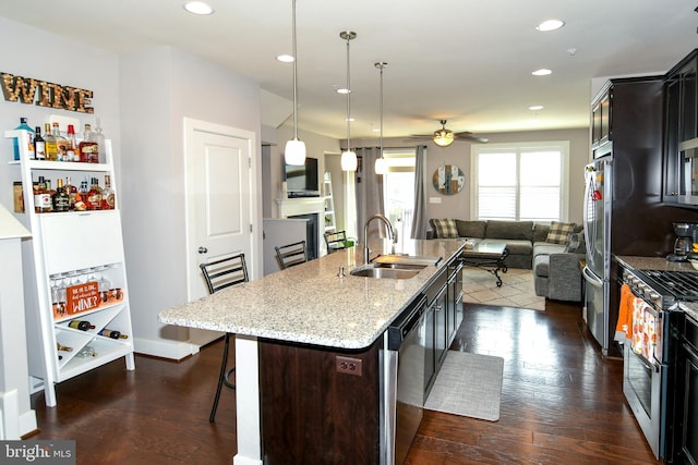 kitchen with sink, dark wood-type flooring, a kitchen breakfast bar, a kitchen island with sink, and appliances with stainless steel finishes