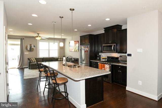 kitchen featuring ceiling fan, sink, a breakfast bar area, a center island with sink, and appliances with stainless steel finishes