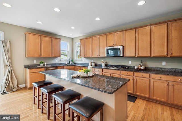 kitchen with sink, light hardwood / wood-style floors, appliances with stainless steel finishes, and a center island