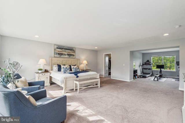 bedroom featuring light carpet and a walk in closet