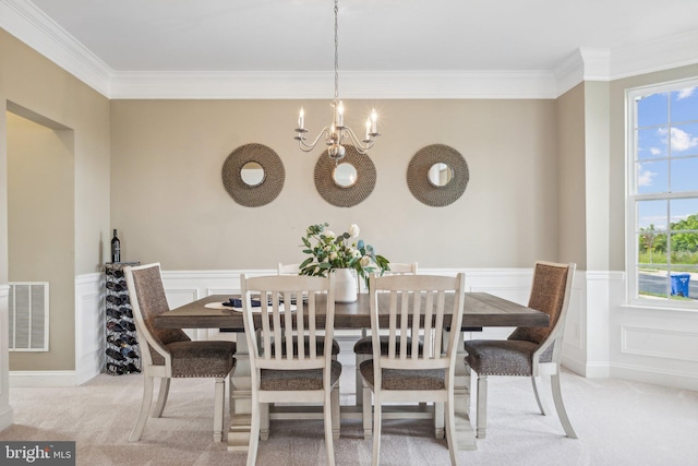 dining room with crown molding, a notable chandelier, and light colored carpet