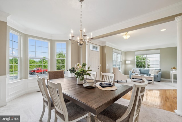 dining space featuring light hardwood / wood-style floors, crown molding, a notable chandelier, and ornate columns